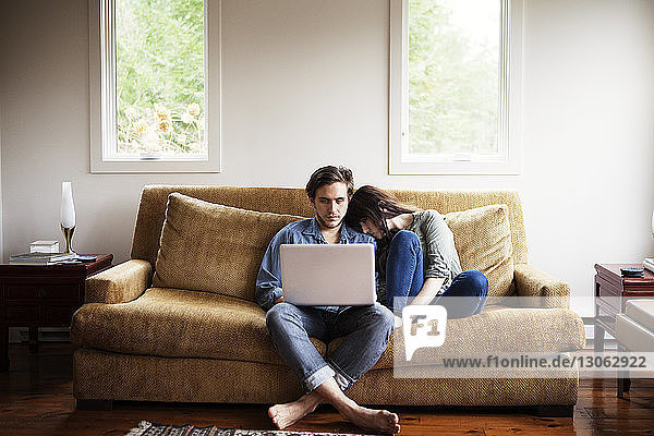 Man using laptop computer while girlfriend leaning on shoulder at home