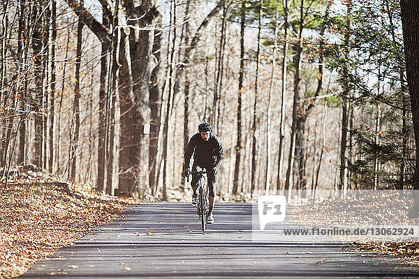 Fahrrad fahrender Sportler auf Straße im Wald