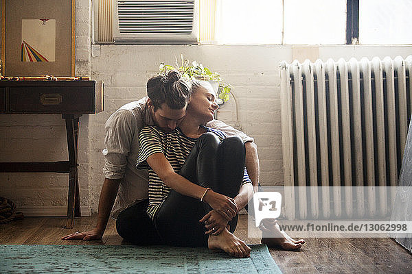 Romantisches Paar sitzt zu Hause auf dem Boden