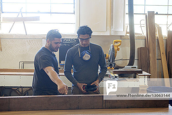 Männliche Schreiner diskutieren auf Workshop über Holzbohlen