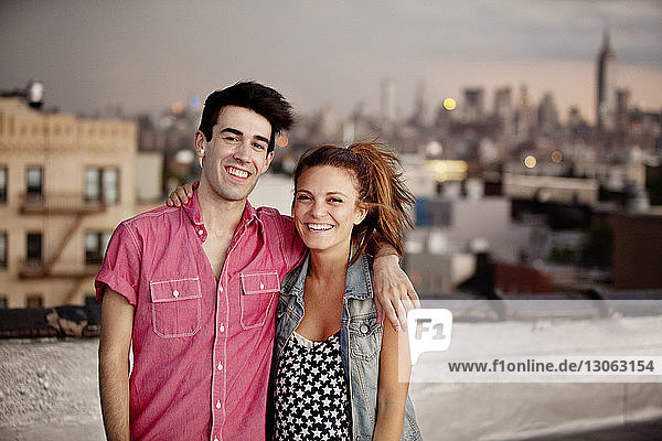Porträt eines glücklichen jungen Paares  das auf der Gebäudeterrasse die Arme umkreist