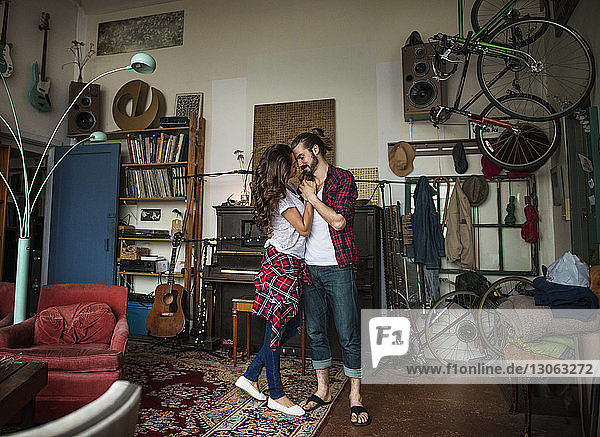 Junges Paar umarmt sich im Stehen zu Hause