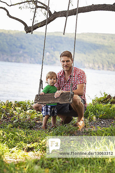 Porträt von Vater und Sohn bei der Seilschaukel am Seeufer