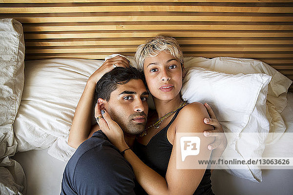 High angle portrait of couple lying on bed at home