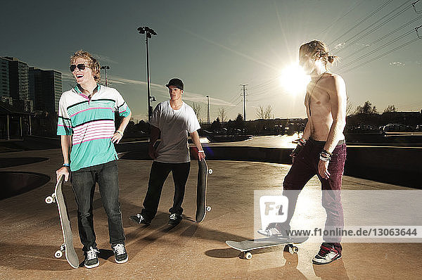 Freunde mit Skateboard auf der Sportrampe bei Sonnenuntergang