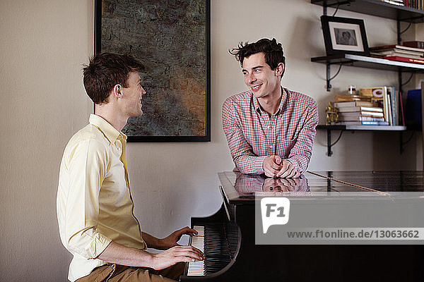 Schwuler Mann schaut seinen Klavier spielenden Freund an