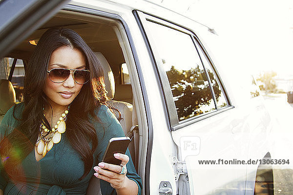 Frau benutzt Smartphone  während sie im Auto sitzt