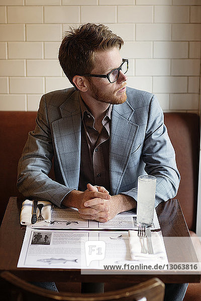 Nachdenklicher Mann schaut weg  während er am Tisch im Restaurant sitzt