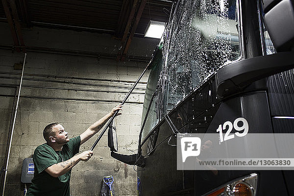 Man cleaning bus in workshop