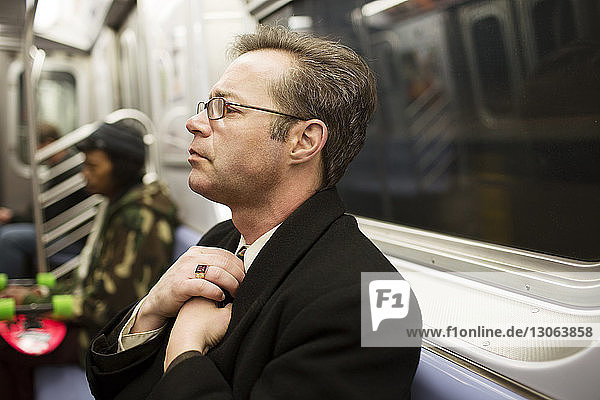 Businessman adjusting necktie in train