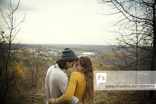 Smiling couple embracing while standing in forest