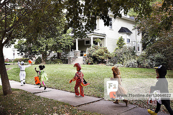 Kinder  die Halloween-Kostüme tragen und auf dem Weg zum Haus während eines Streiches oder einer Behandlung laufen