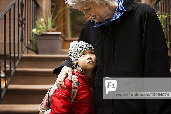 Enkelin schaut Großmutter an  während sie auf Stufen steht
