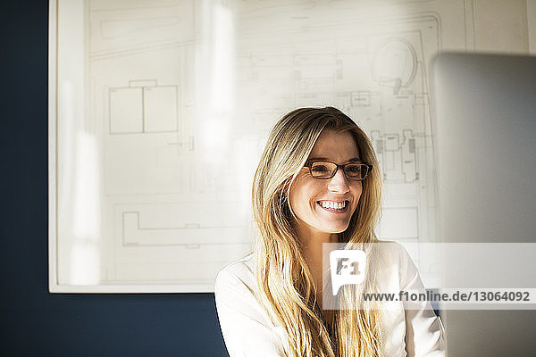Happy woman using desktop computer while working in office