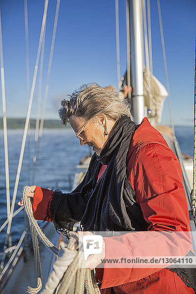 Side view of senior woman holding rope in yacht on sea