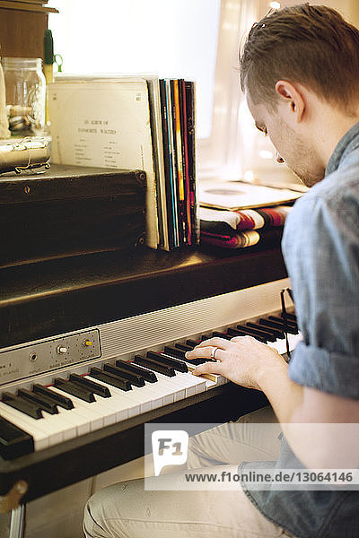 Side view of man playing piano at home