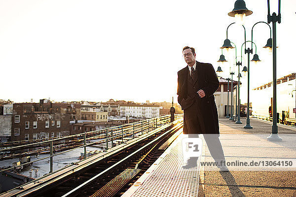 Geschäftsmann wartet in U-Bahn-Station bei klarem Himmel auf Zug