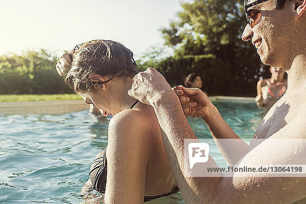 Glücklicher Mann schnürt Bikini-Oberteil einer Frau beim Schwimmen