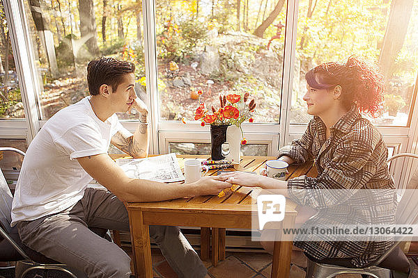 Hochwinkelansicht eines Paares  das zu Hause am Tisch sitzt und die Hand hält