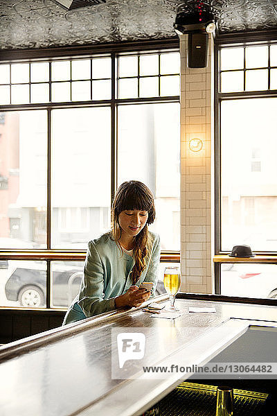 Frau benutzt Mobiltelefon  während sie in einer Bar sitzt