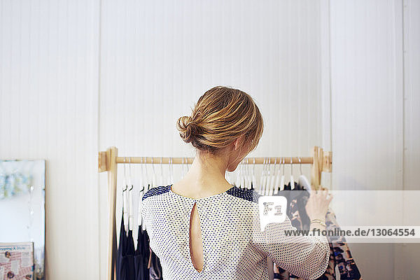 Rear view of woman arranging clothes in rack