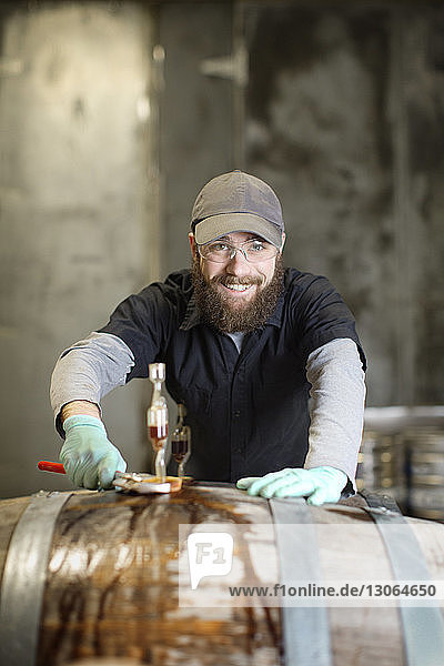 Porträt eines glücklichen Mannes  der Fässer in einer Brauerei repariert