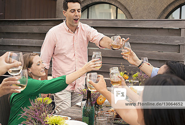 Friends toasting wineglasses while enjoying meal at table