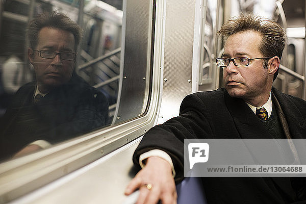 Businessman looking away while traveling in train