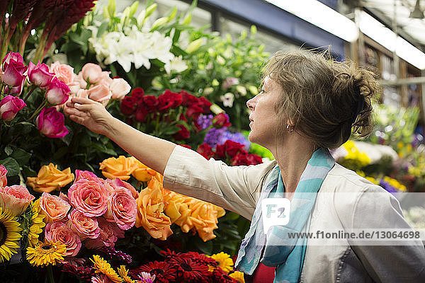 Frau kontrolliert Blumen am Marktstand