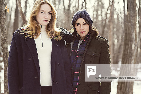 Portrait of friends standing in forest during winter