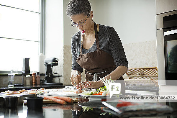 Frau zerkleinert Fleisch bei der Zubereitung von Speisen zu Hause