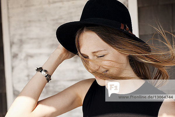 Woman holding sun hat against wooden wall