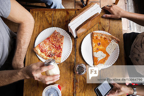 Mitsektion von Freunden beim Pizzaessen am Holztisch im Restaurant