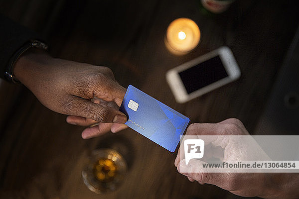 Ausgeschnittenes Bild einer Hand  die dem Barkeeper in einer Bar eine Kreditkarte gibt
