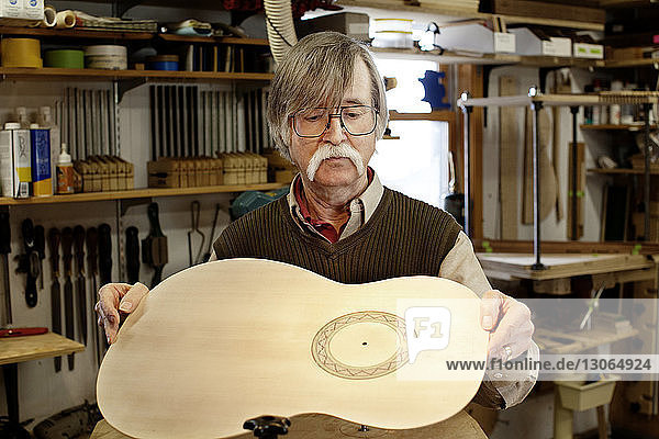 Mann fertigt Gitarre in Werkstatt
