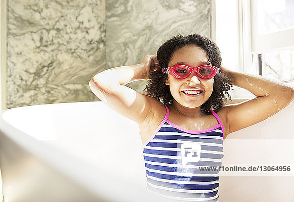 Porträt eines fröhlichen Mädchens mit Schwimmbrille  das in der Badewanne sitzt