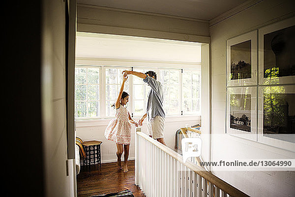 Vater tanzt mit glücklicher Tochter auf dem Flur am Fenster zu Hause
