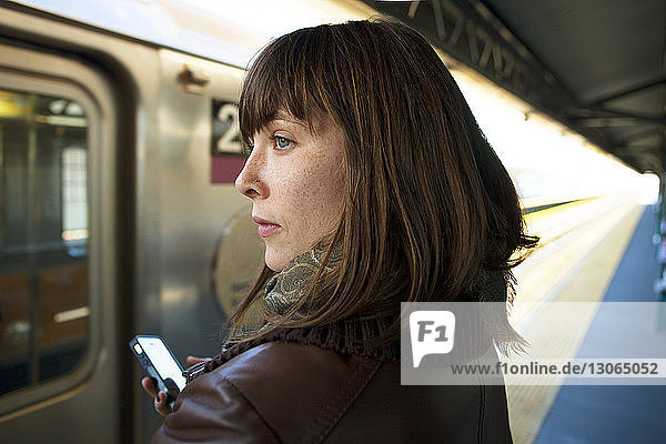 Frau schaut weg  während sie am Bahnhof auf den Zug wartet