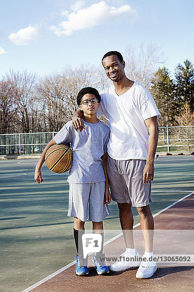 Porträt von Vater und Sohn im Basketballplatz stehend