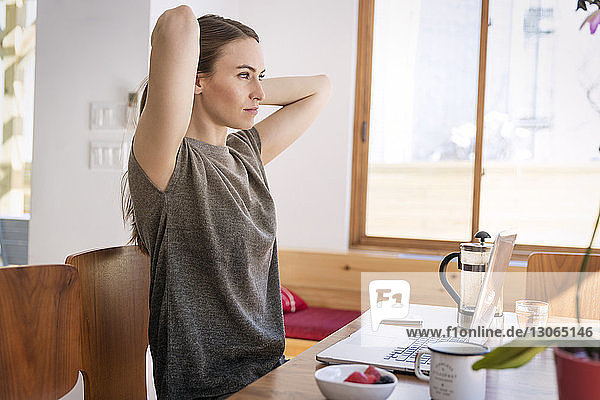 Woman looking away while sitting at table in home