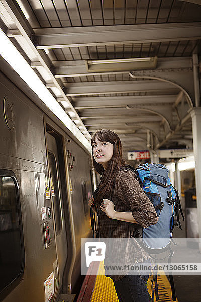 Frau sieht Zug an  während sie auf Bahnsteig steht