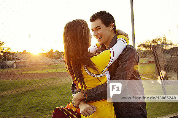 Man embracing woman while standing against playing field