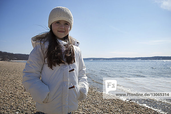 Cute girl standing at beach against sky
