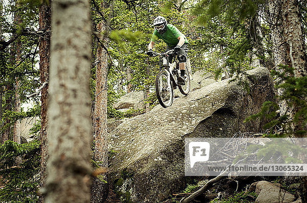Man moving down rocks while cycling in forest