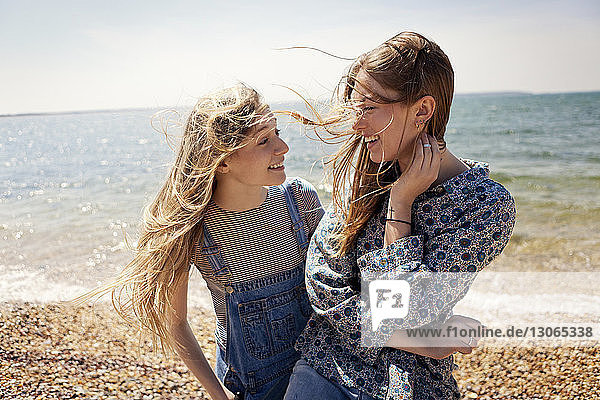 Happy friends talking while standing at beach