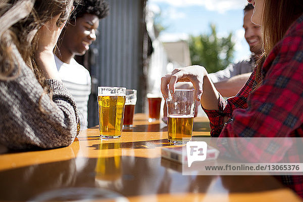 Freunde trinken an sonnigen Tagen Bier bei Tisch in der Brauerei