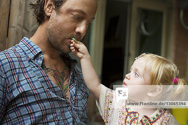 Kleines Mädchen füttert Vater zu Hause