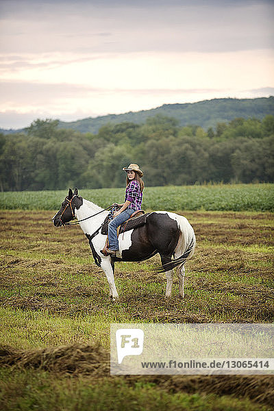 Seitenansicht eines auf einem Pferd sitzenden Cowgirls