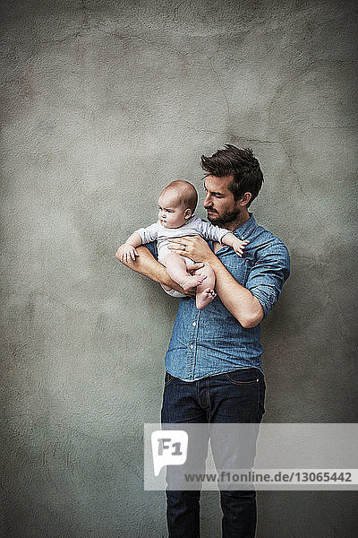 Mann trägt Sohn  während er an der Wand steht