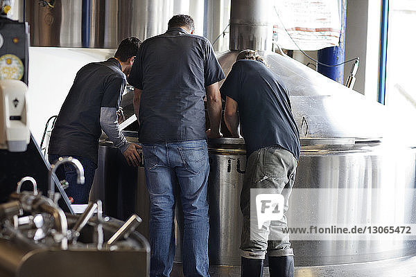 Rückansicht von Männern  die am Lagertank in einer Brauerei arbeiten